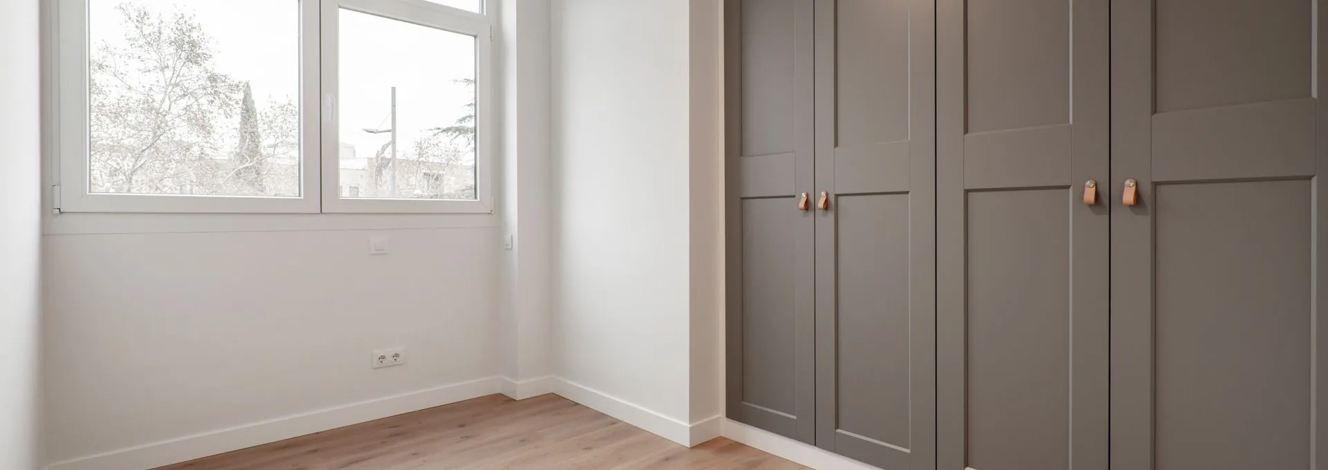 Lichte kamer met een kamerhoge inbouwkast met taupe paneeldeuren