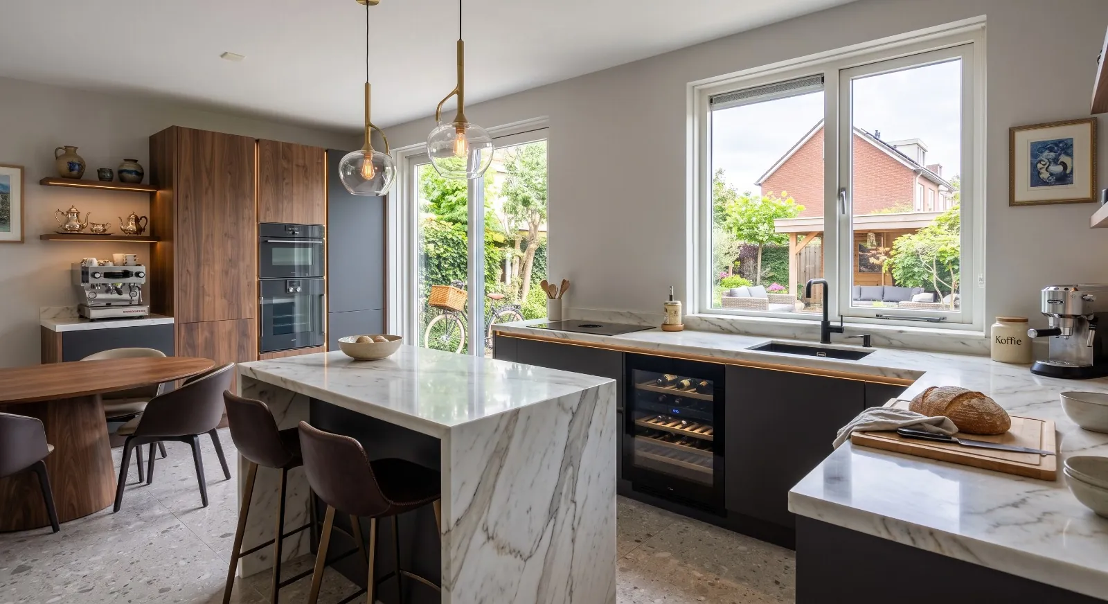 Keuken met een marmeren eiland, donkere fronten en uitzicht op de tuin